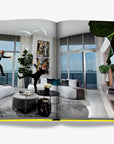 Stylish couple in an ultra-modern Miami penthouse, playfully jumping in a contemporary setting with stunning ocean views. Featured in the Assouline Coffee Table Book Miami Beach, available at Spacio India.