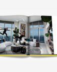 Stylish couple in an ultra-modern Miami penthouse, playfully jumping in a contemporary setting with stunning ocean views. Featured in the Assouline Coffee Table Book Miami Beach, available at Spacio India.