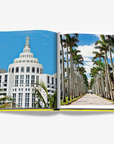 Iconic Miami Art Deco building with white geometric architecture and palm tree-lined avenues, representing the city's architectural legacy. Captured in the Assouline Coffee Table Book Miami Beach, available at Spacio India.