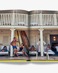 A lively poolside scene at a luxurious Miami beach house, with sun loungers, surfboards, and socializing guests, embodying the city's relaxed lifestyle. From the Assouline Coffee Table Book Miami Beach, available at Spacio India.