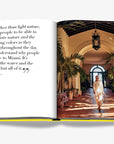 Serene courtyard with lush tropical greenery and classic Spanish-inspired arches, bathed in golden sunlight. Part of the Assouline Coffee Table Book Miami Beach, available at Spacio India.