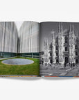 A double spread of a contrasting architectural featuring a modern building with a sleek, blurred facade on the left and a black-and-white photograph of Milan's iconic Duomo cathedral on the right in a luxurious Assouline Milan Chic coffee table book, showcasing Milan’s timeless elegance, now available at Spacio India’s online store and retail outlets.