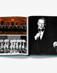 A double spread elegant performance with glowing lights, vintage showgirls in feathered costumes and singer performing in a luxurious Assouline's Monte Carlo coffee table book, featuring a vibrant cover with images of Monaco's iconic landmarks, available at Spacio India.