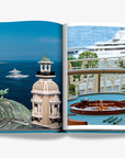 Stunning views of Monaco’s historic architecture, luxury yachts, and a classic casino roulette table on a double spread page of a luxurious Assouline's Monte Carlo coffee table book, featuring a vibrant cover with images of Monaco's iconic landmarks, available at Spacio India.