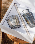 An art nouveau atmosphere is created on a wooden table, where a Baobab Brussels My First Baobab MFBBOXBRU scented candle and fragrance diffuser are neatly placed inside a delicate box.