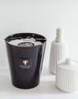 A fragrant Baobab Encre De Chine MAX16ENC candle sits next to a white candle on a table.