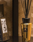 Styled Baobab Aurum Diffuser 500ml on a bookshelf beside art books, enhancing interiors with jasmine and musk fragrance, now offered at Spacio India.