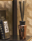 Baobab Cyprium Diffuser 500ml positioned on a bookshelf next to premium art books, enhancing interiors with its warm metallic elegance; available from Baobab Collection at Spacio India.