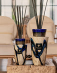 Two sizes of Baobab Stones Lazuli Diffuser Totem on wooden tables, accentuating luxury home styling with deep blue glass detailing, purchasable at Spacio India.