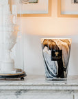Baobab Stones Marble Candle Max 24 elegantly displayed on a marble fireplace black and white glass vessel with leather, rose, and plum aroma, sold at Spacio India stores and online.