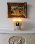 Baobab White Pearls Candle placed on a mantel beneath a painting, casting a soft glow – floral luxury fragrance by Baobab at Spacio India.