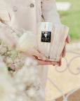 Elegant hand holding Baobab White Pearls Candle Max 16 outdoors, symbolising refined taste and floral elegance, now at Spacio India.