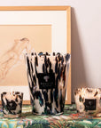 Artistic arrangement of Baobab Black Pearls Candle Max 10 with other sizes on vibrant tropical patterned surface, bringing luxurious fragrance to interiors. Buy at Spacio India.