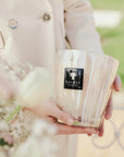 Elegant hand holding Baobab White Pearls Candle Max 16 outdoors, symbolising refined taste and floral elegance, now at Spacio India.