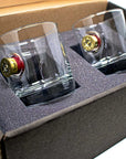 Two whiskey glasses with bullet in a box