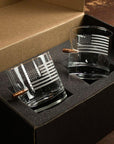 Two glass tumblers with American flag engraving on a black cushioned surface.