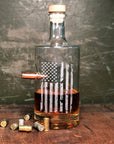 Glass whiskey decanter with American flag design and bullet on a wooden surface