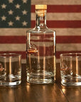 Whiskey decanter and 2 whisky glass with bullets in front of American flag background