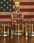 Whiskey decanter and 2 whisky glass with bullets in front of American flag background