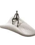 A captivating Butzon & Bercker Sculpture Intuition of a man sitting on a sand dune, crafted by Butzon Bercker.
