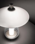 Modern table lamp with a white shade and black base on a dark surface.