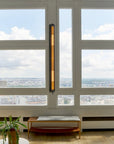 In the tube wall light from DCW Editions on a wall with windows showing city view