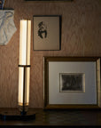 La Lampe Frechin table lamp by DCW Editions upright on a console table with photo frame and art works on wall.