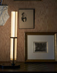 La Lampe Frechin table lamp by DCW Editions upright on a console table with photo frame and art works on wall.