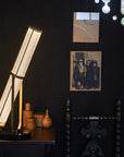La Lampe Frechin table lamp by DCW Editions on a side table in a dark theme interior.