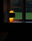 A small lamp from DCW Editions on a windowsill with a dark background