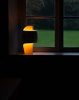 A small lamp from DCW Editions on a windowsill with a dark background