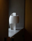 White abstract table lamp on a dark surface with a dark background