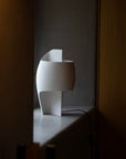 White abstract table lamp on a dark surface with a dark background