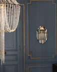 Chandelier and wall mirror reflection on a blue paneled wall
