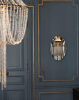 Chandelier and wall mirror reflection on a blue paneled wall