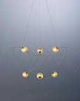 Modern chandelier with five spherical lights on a gray background from DCW Editions