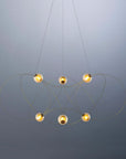 Modern chandelier with five spherical lights on a gray background from DCW Editions