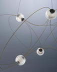 Modern chandelier with glass shades and gold cables against a gray background