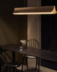Respiro suspension lamp in brass from DCW Editions above a long black table