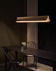 Respiro suspension lamp in brass from DCW Editions above a long black table