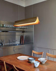 Respiro suspension lamp in brass from DCW Editions above a dining table