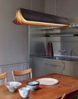 Respiro suspension lamp in brass from DCW Editions above a dining table