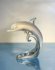 Glass dolphin sculpture on a reflective surface with a blurred background