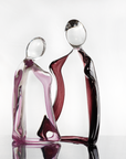Artistic glass sculpture of two abstract figures titled Him & Her from Duccio Di Segna on a white background available at Spacio retail stores in Mumbai & Kolkata.
