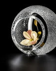 Decorative glass vase with textured design holding a flower on a black background