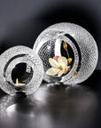 Two crystal candle holders with a flower and candle on a dark background