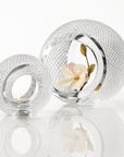 Two crystal sculptural candle holders with textured design on a white background