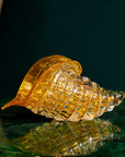 Duccio Di Segna crystal Cornucopia in amber and gold, displayed on a green table, available at Spacio India - luxury crystal glass decor sculpture
