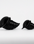 Two glossy black crystal spiral shell-shaped decorative objects displayed side by side on a clean white background.