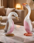 Two decorative duck figures on a marble surface with a blurred living room background.